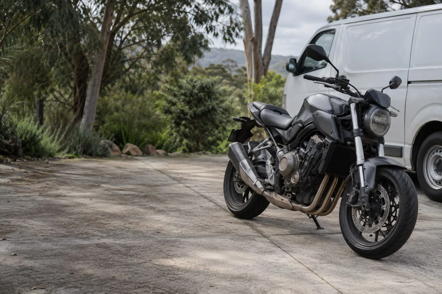 Illustrative photograph of a used motorcycle beside an unbranded van on an Australian driveway.